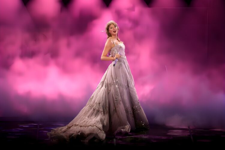Taylor Swift in a flowing violet fairytale gown, dreamy stage backdrop.
