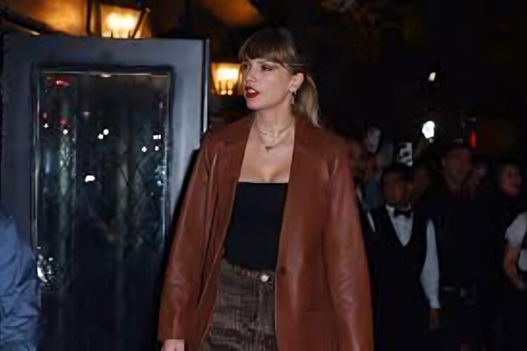 Taylor Swift walking in the city at night, wearing relaxed knit sweater, leather jacket.