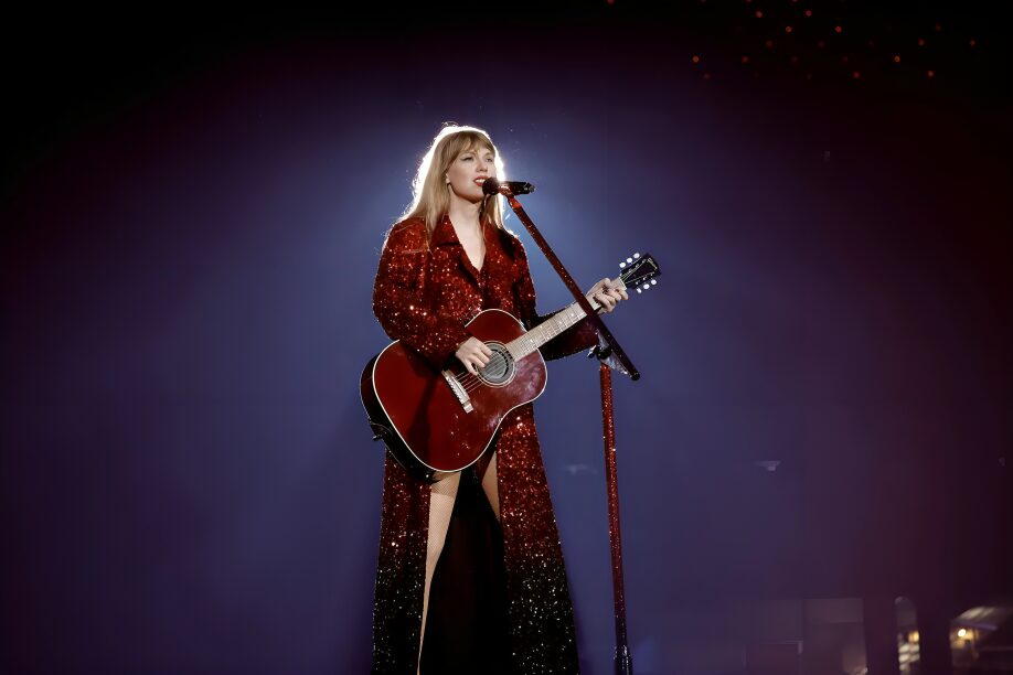 Taylor Swift in a long glittering midnight cloak, sparkling and dramatic.