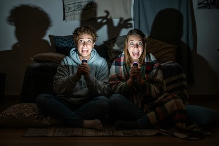 A dark room lit only by flashlights under the couple’s faces.