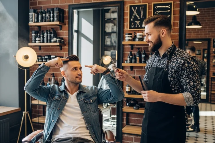 Man explaining haircut style to barber using hand gestures, calm confident discussion.