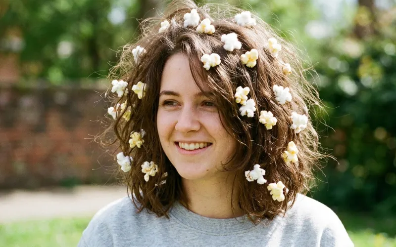 “hair covered with cotton ‘popcorn’ pieces, playful messy look, bright lighting, realistic image”