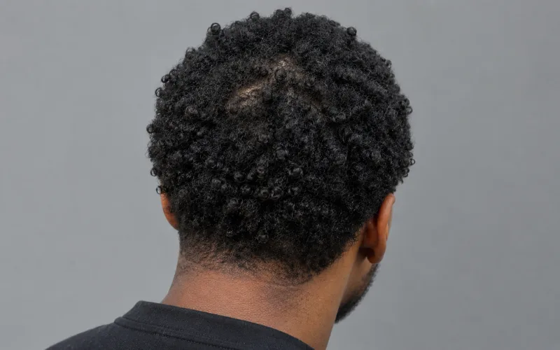 Man with tightly coiled natural hair viewed from behind.