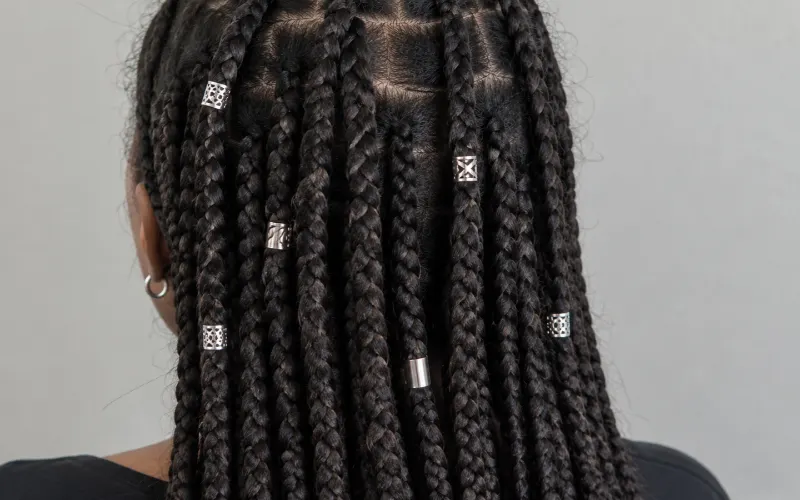Silver hair cuffs decorating dark box braids, showcasing stylish hair jewelry.